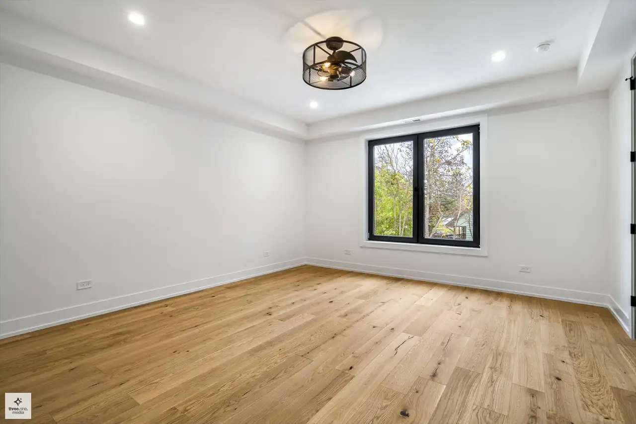 Unfurnished bedroom with a tray ceiling and single black-framed window