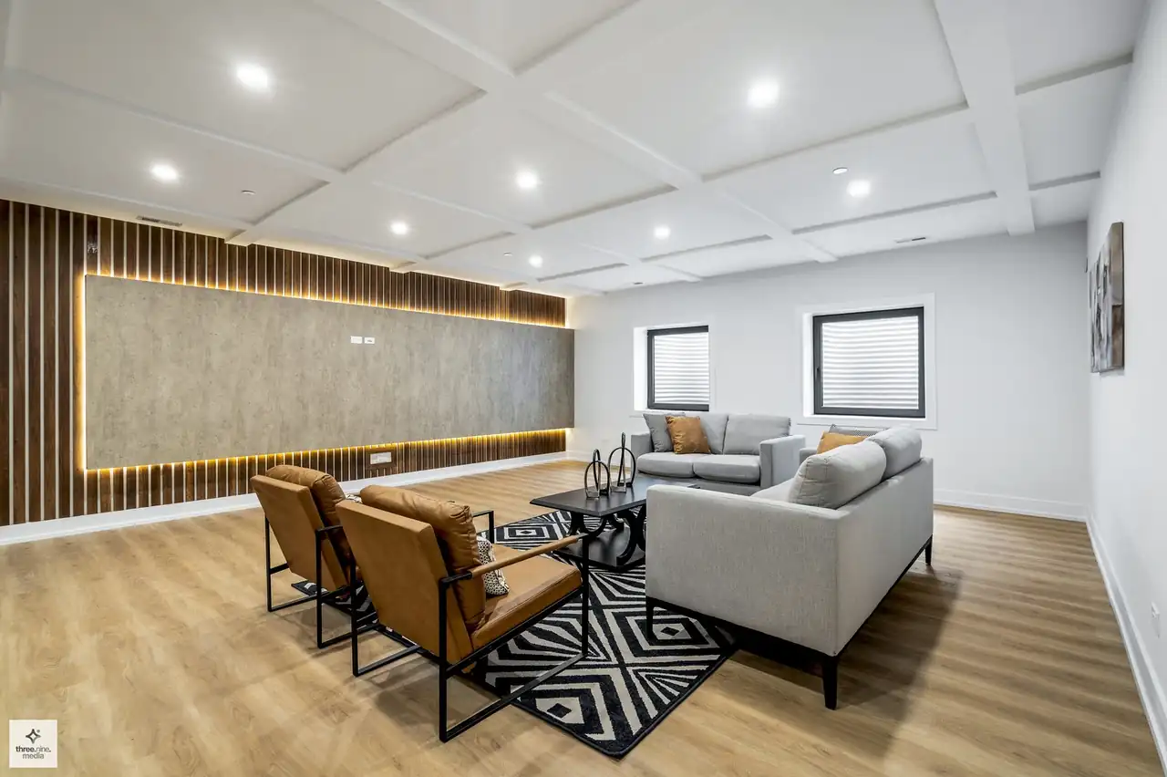 Lower-level lounge with a backlit wood slat accent wall and sectional seating