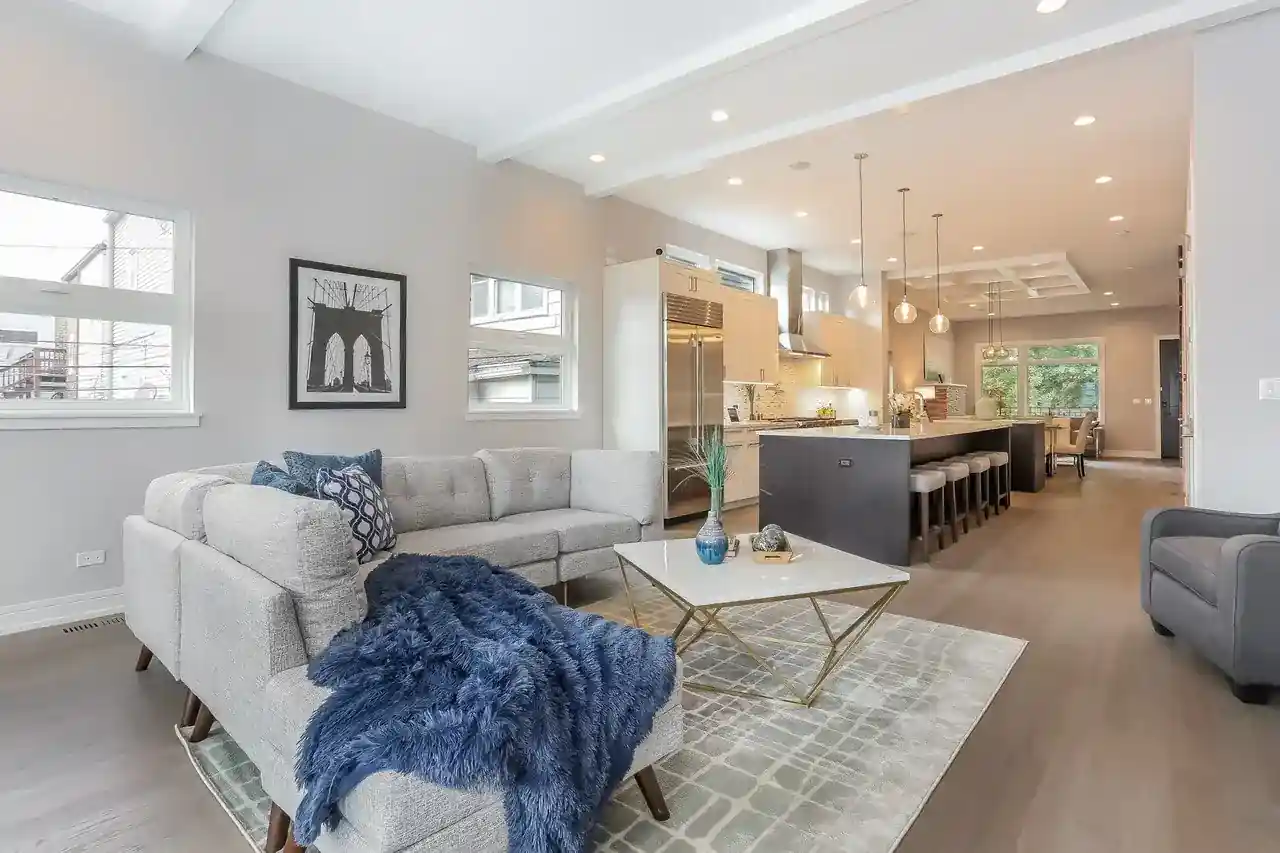 Open-concept living room with gray sectional sofa and view into kitchen with island seating