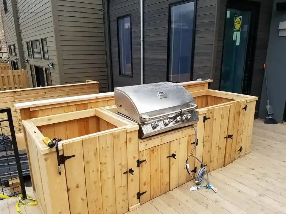 Custom cedar outdoor kitchen structure with a built-in gas grill on the rear deck