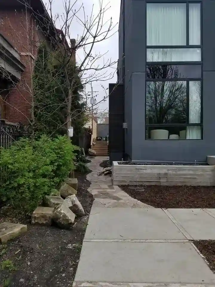 Side yard walkway leading to the Humboldt Park addition, showing the gray exterior wall and new landscaping