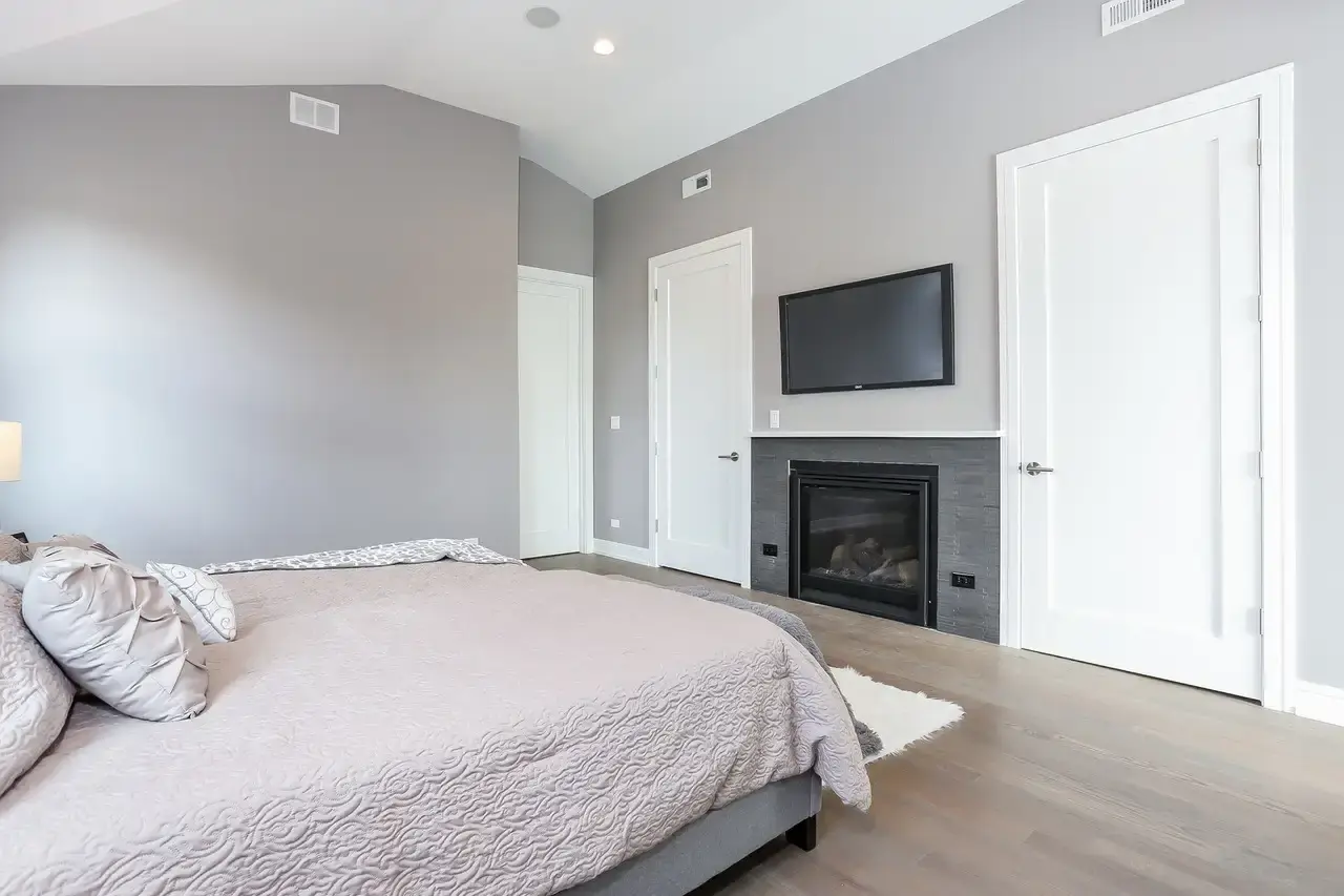 Primary bedroom with gas fireplace, wall-mounted TV, and white paneled doors
