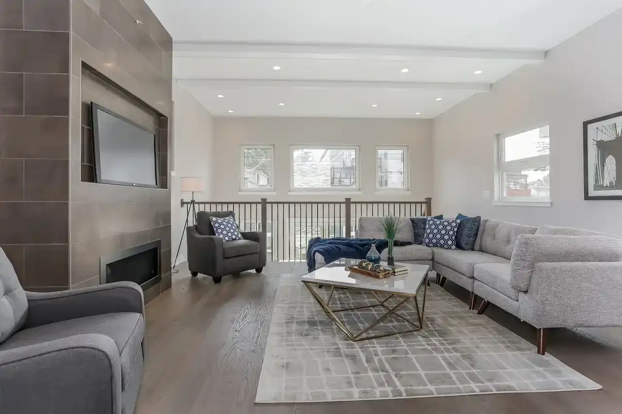 Upstairs loft living room with tiled fireplace wall, TV, sectional sofa, and railing overlooking lower level