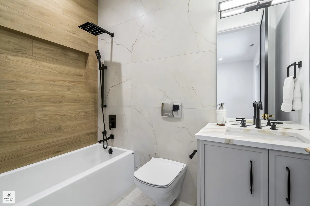 Tub-shower combo with wood-look tile accent and matte black fixtures
