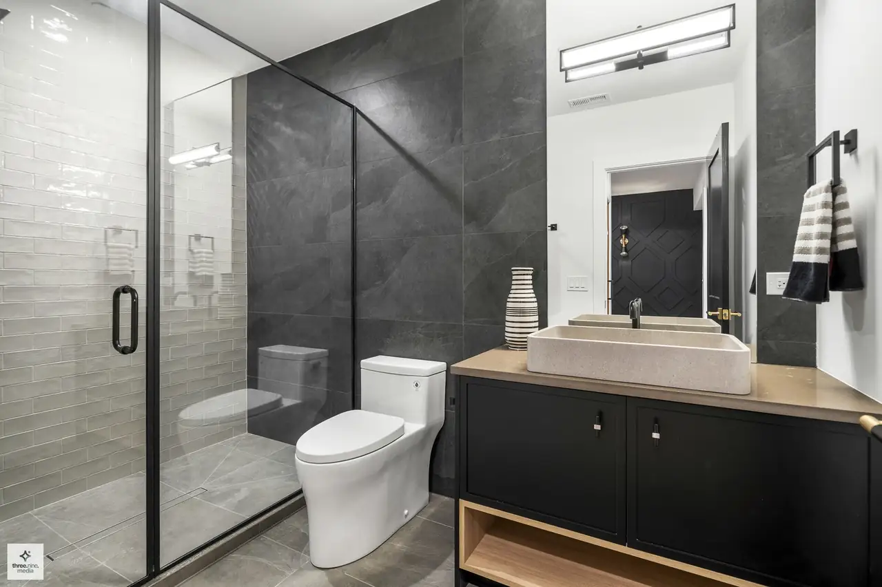 Bathroom with a charcoal tile shower and a stone vessel sink vanity