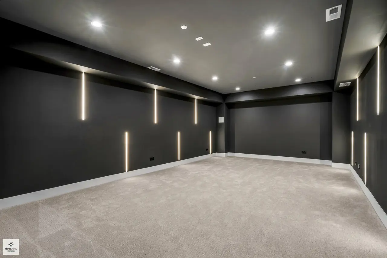 Unfinished lower-level theater room with vertical light strips along dark walls