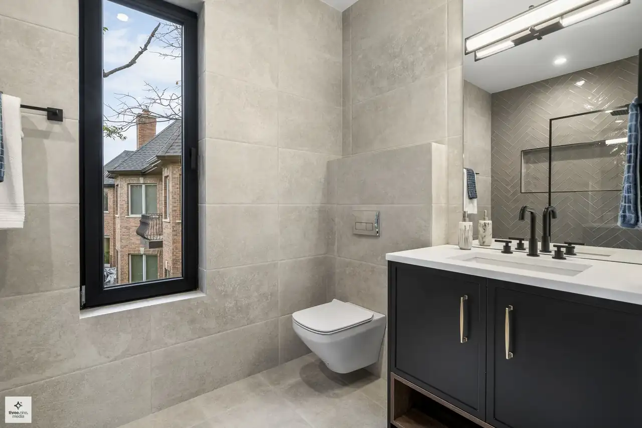 Bathroom with taupe stone tile and a herringbone tile mirror backsplash