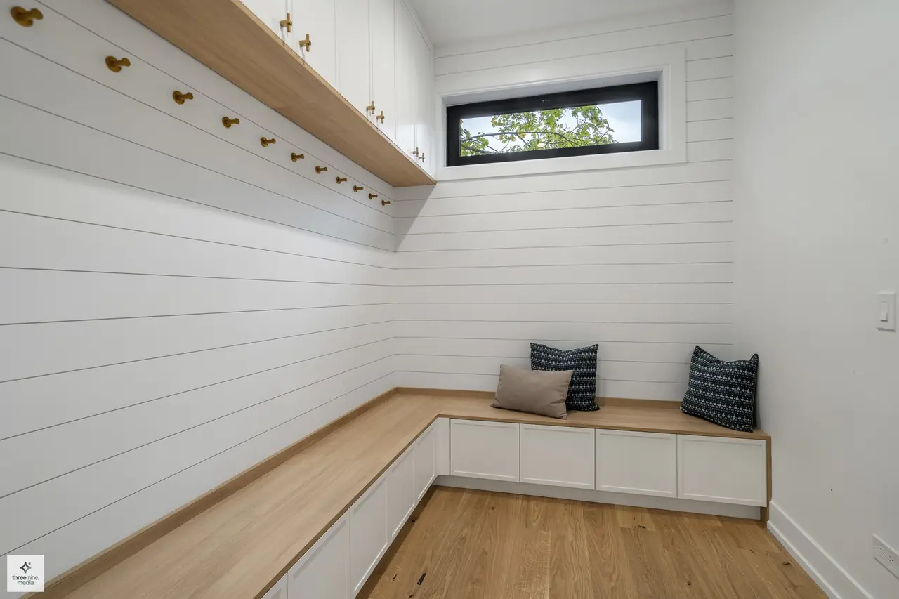 Mudroom with a built-in bench, brass hooks, and shiplap paneling