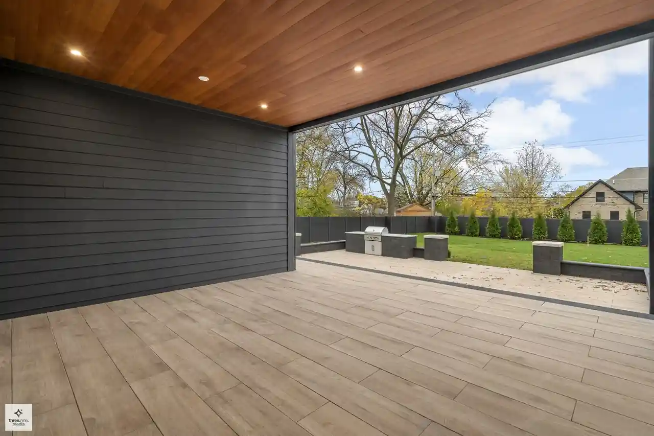 Covered outdoor living area with a wood ceiling opening to the grill patio
