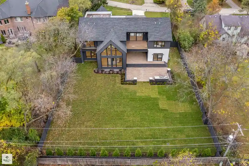 Aerial view of the fenced backyard lawn framed by evergreen landscaping