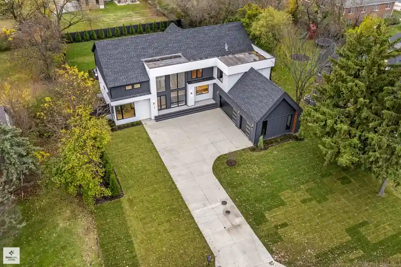 Aerial view of the rear roofline, patio, and driveway approach