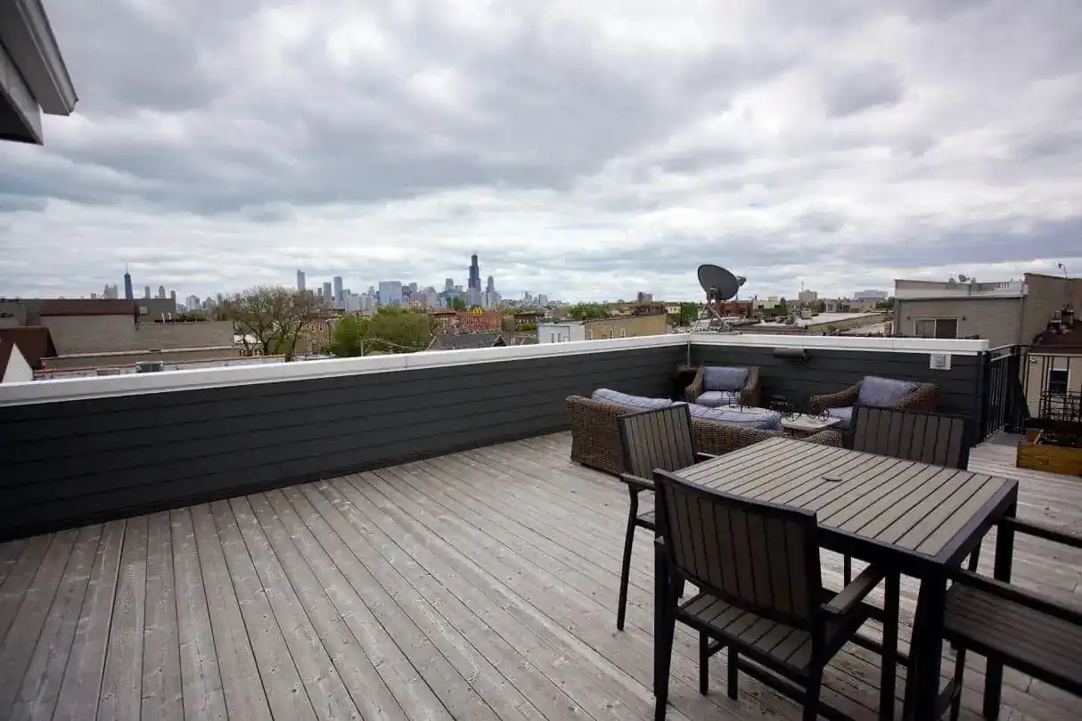 Rooftop deck with outdoor seating, dining table, and downtown skyline view at a Rice multifamily development