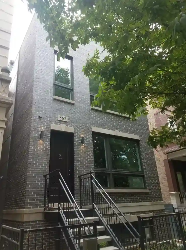 Exterior of Mozart Residence new construction townhome with gray brick facade, black steel railings, and covered entry