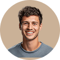 Smiling young man with short curly hair wearing a gray shirt against a beige background.