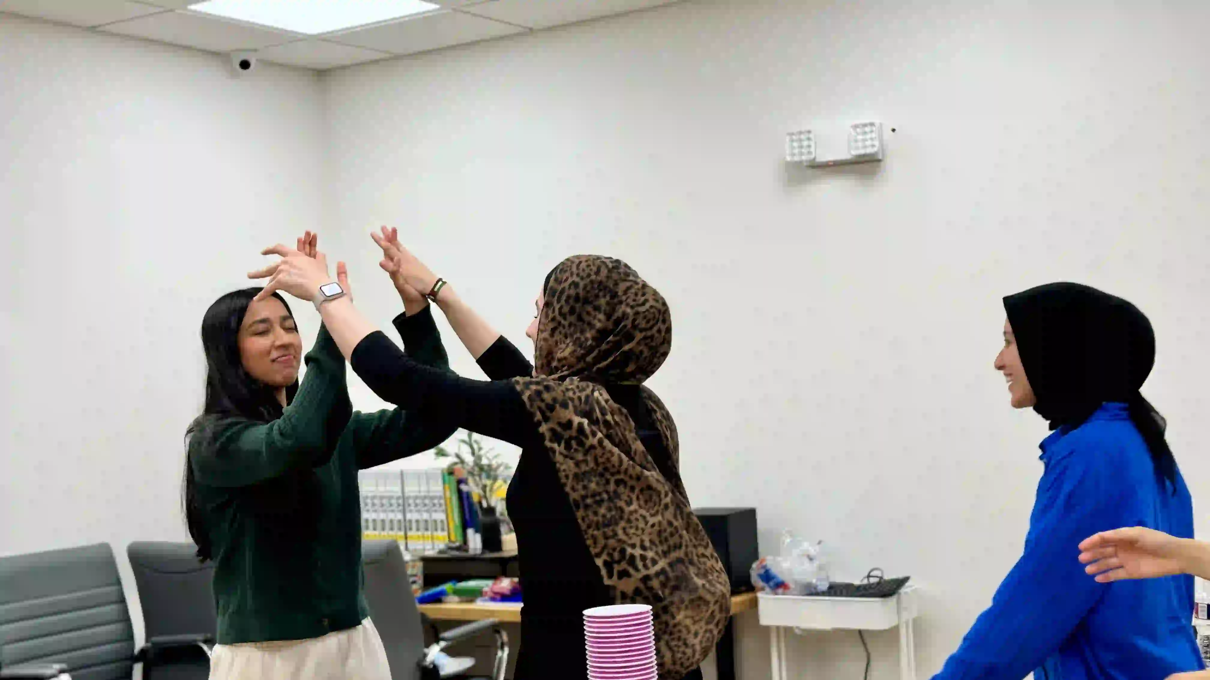three girls practicing a dance with hands raised