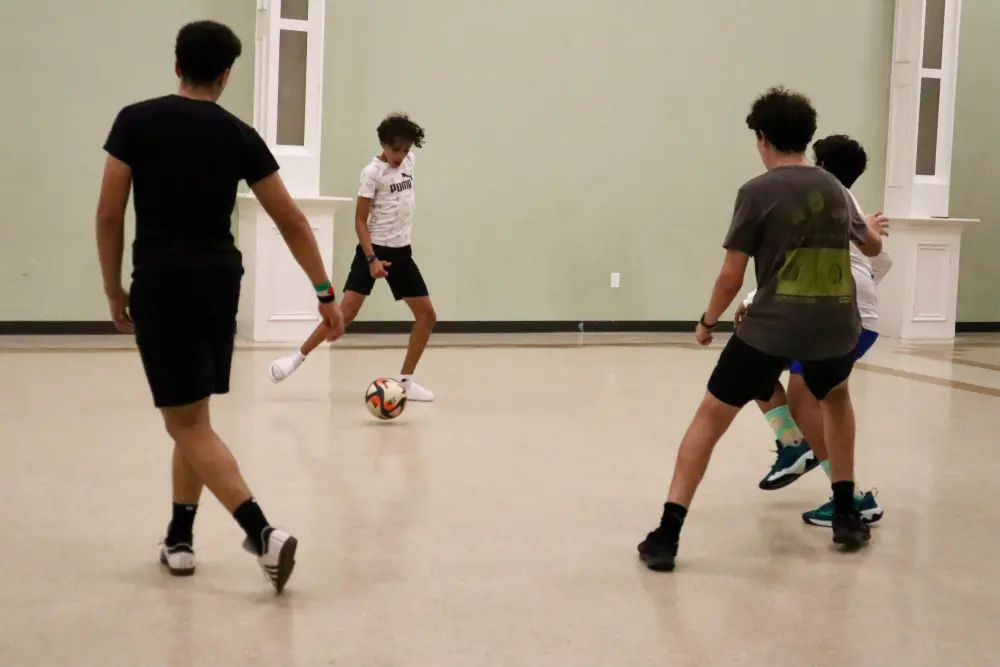 three boys playing sports in an indoor gymnasium