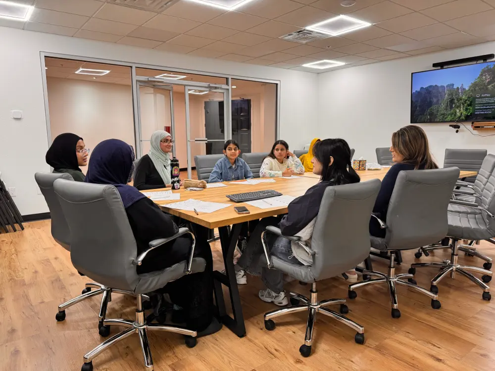 adults and teens seated around a conference table for a meeting