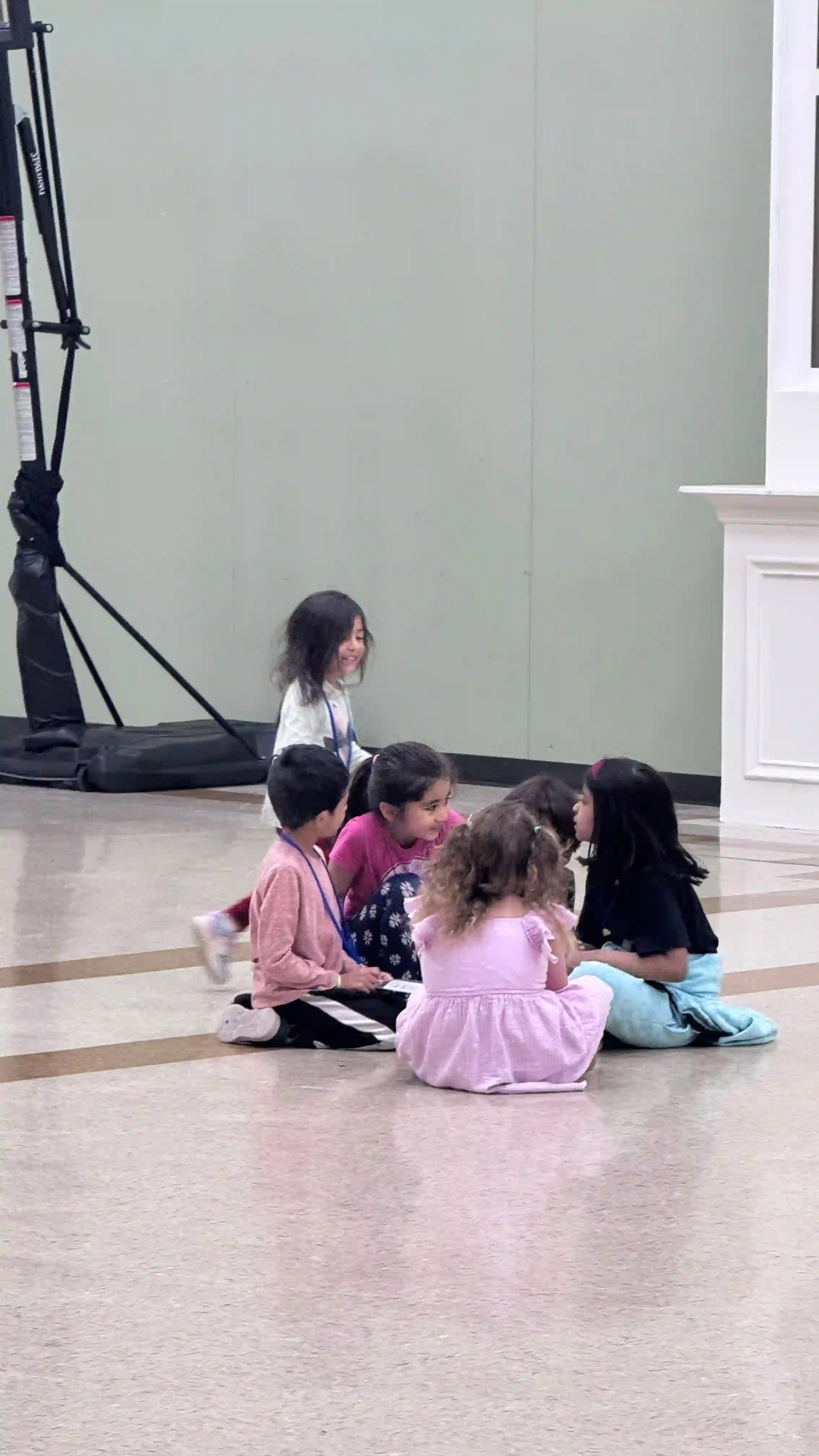 young children sitting together on the floor during group activity in gymnasium
