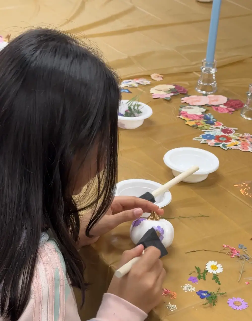 girl painting small ceramic objects at arts and crafts table