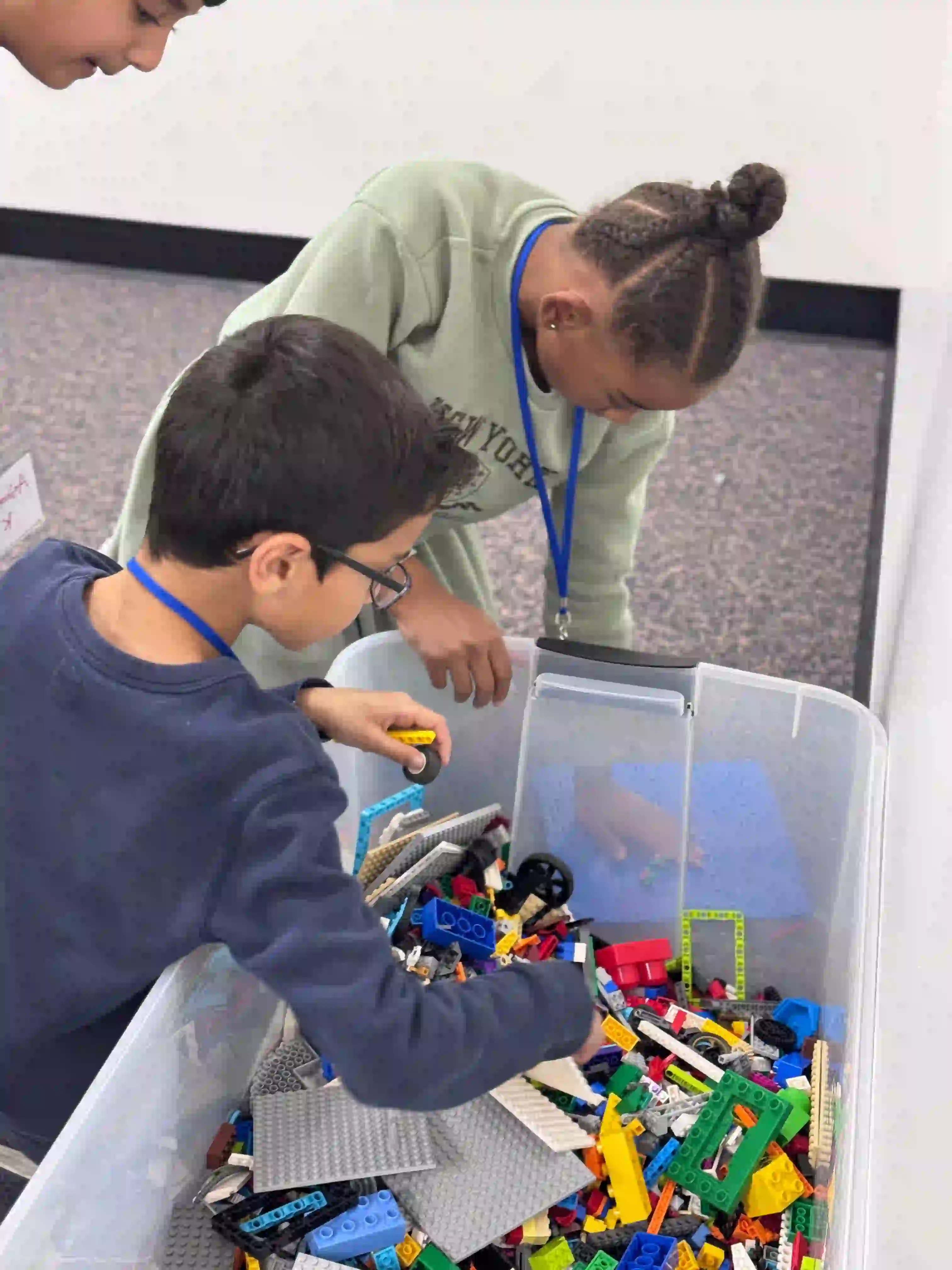 two children sorting colorful lego bricks from a bin during after school activity