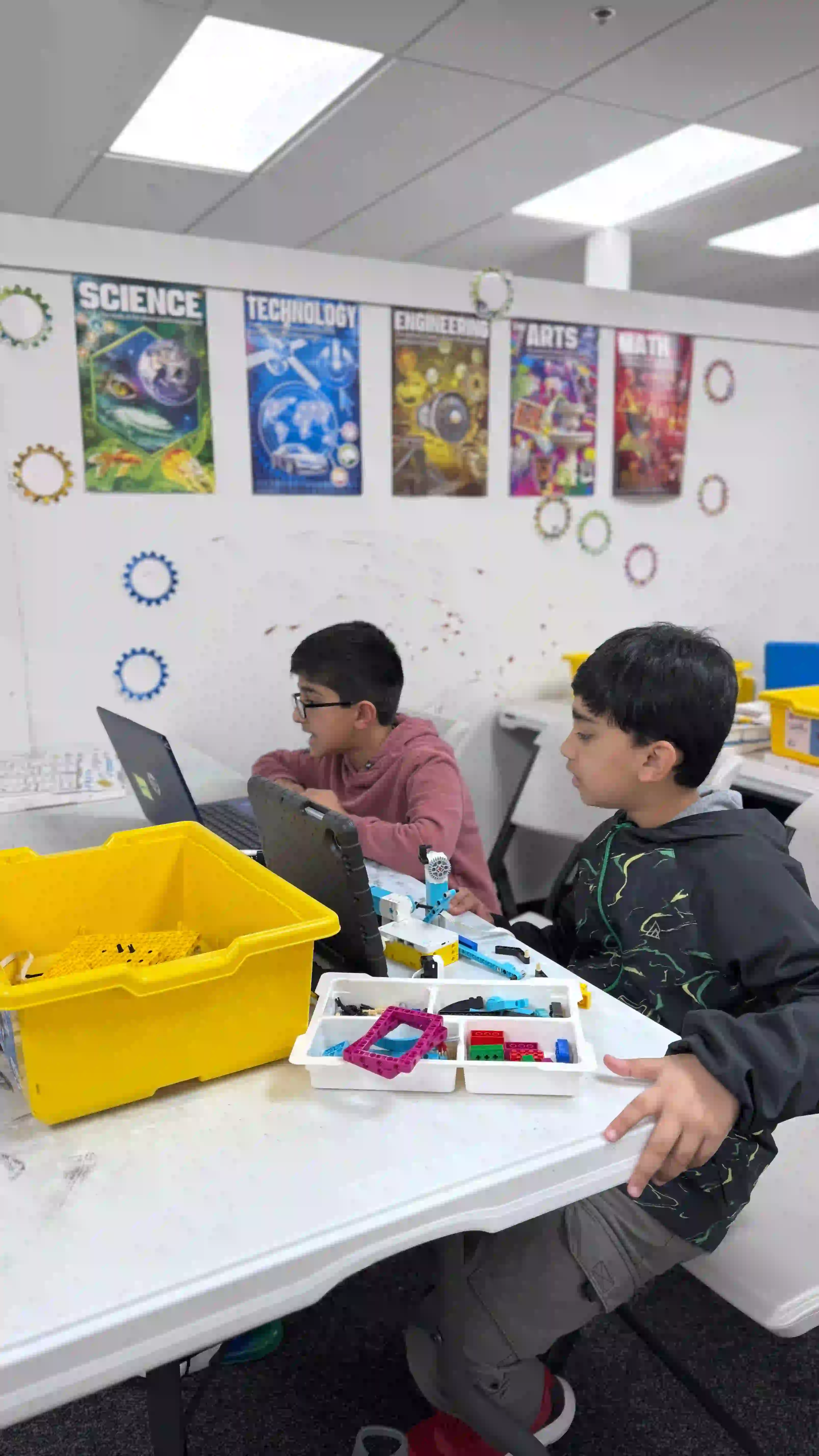 Two students collaborating on a robotics project with building materials