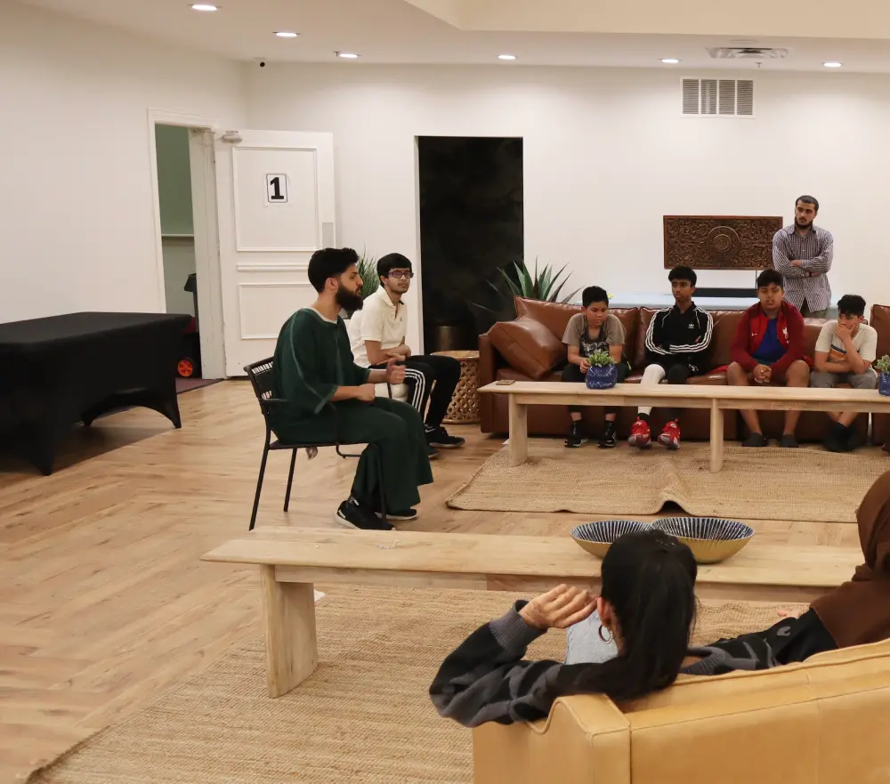Youth mentorship session with a speaker addressing middle schoolers in a cozy, well-lit common area