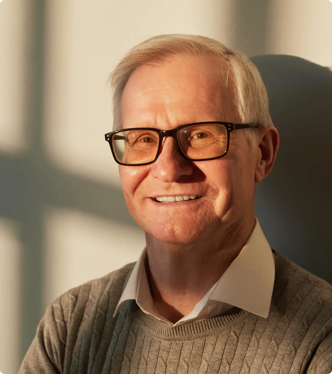 an older man wearing glasses and a sweater