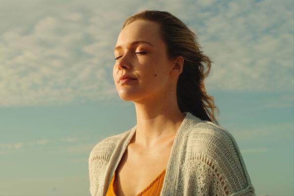 Person standing in the sun, eyes closed