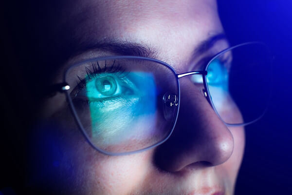 Blue light reflecting on a persons glasses