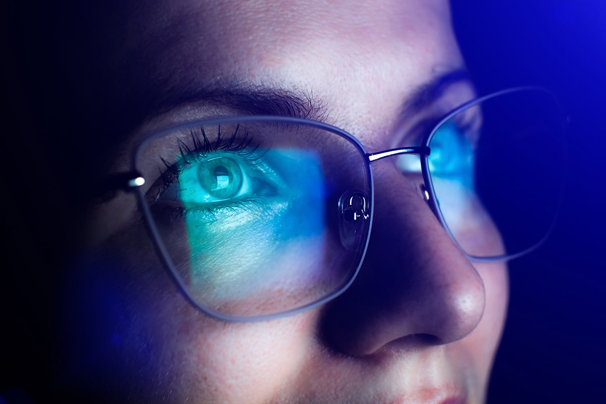 Blue light reflecting on a persons glasses