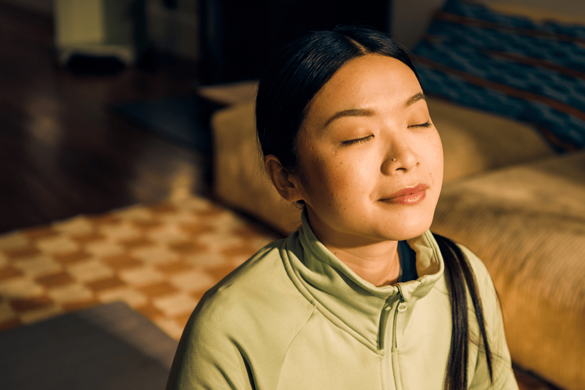 Young woman with closed eyes relaxing, representing burnout prevention and self-care.