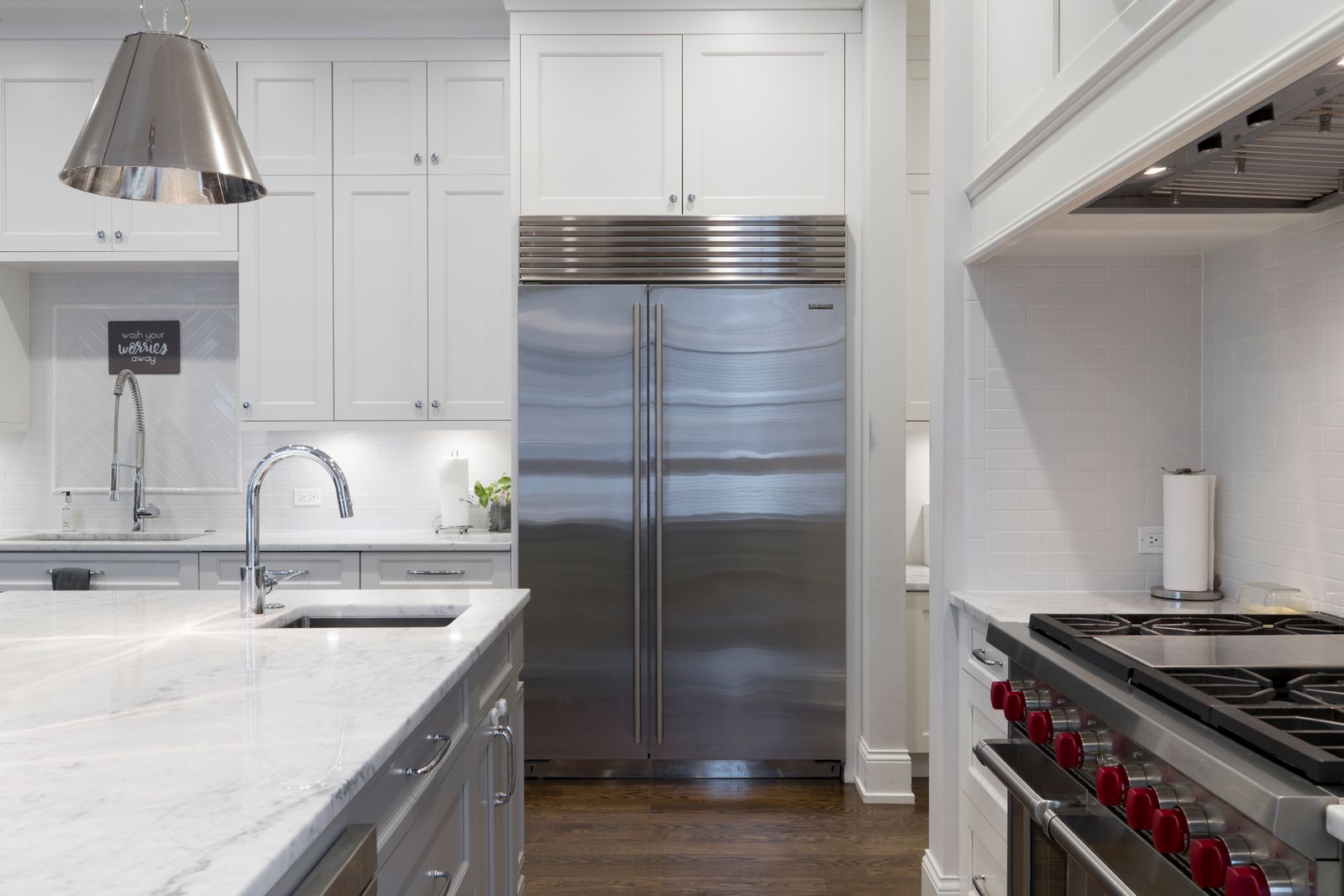 Stainless steel refrigerator beside white cabinets, appliance reference