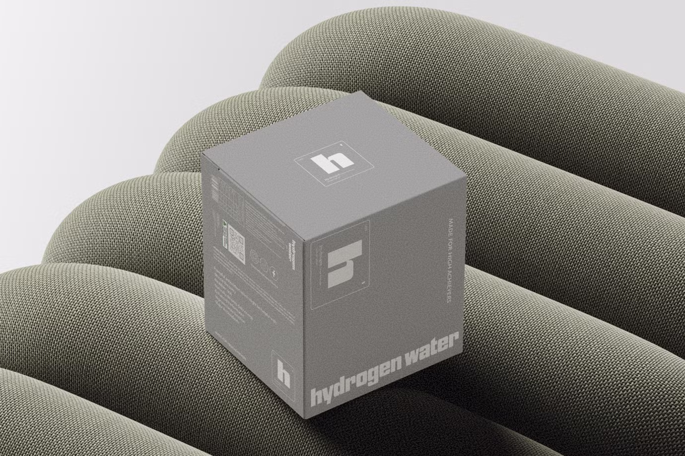 Gray cube box labeled 'hydrogen water' placed on a textured, padded surface.