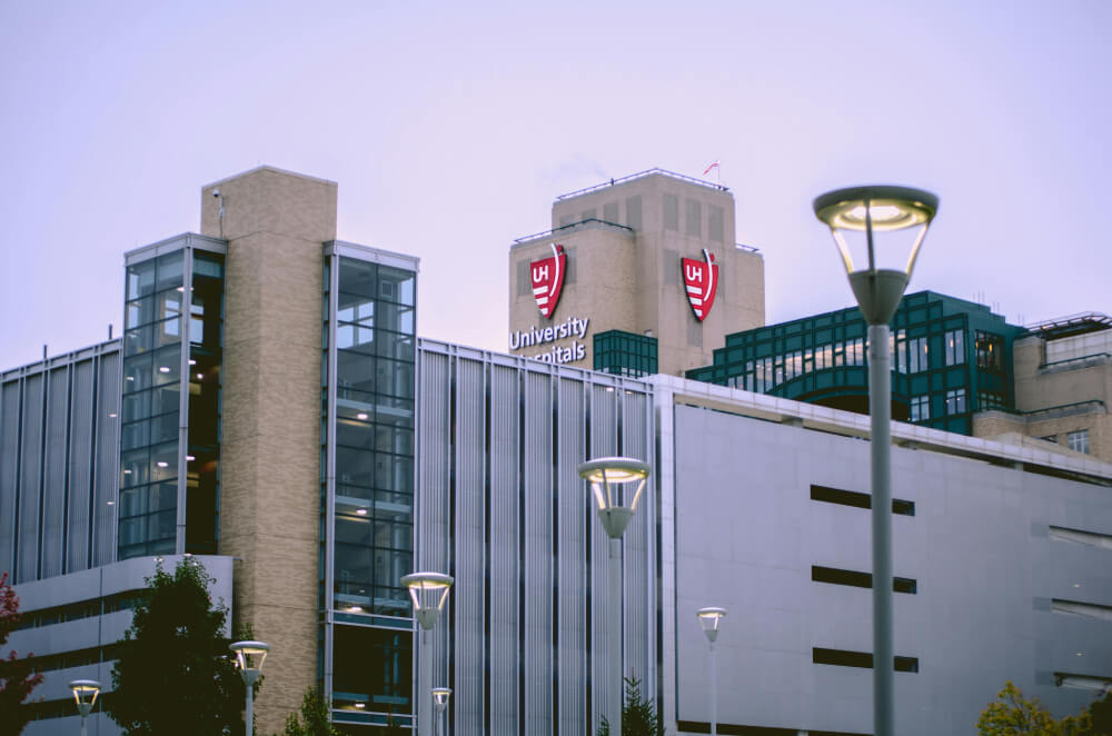 Exterior view of a modern medical building with University Hospitals logo and illuminated street lamps at dusk.