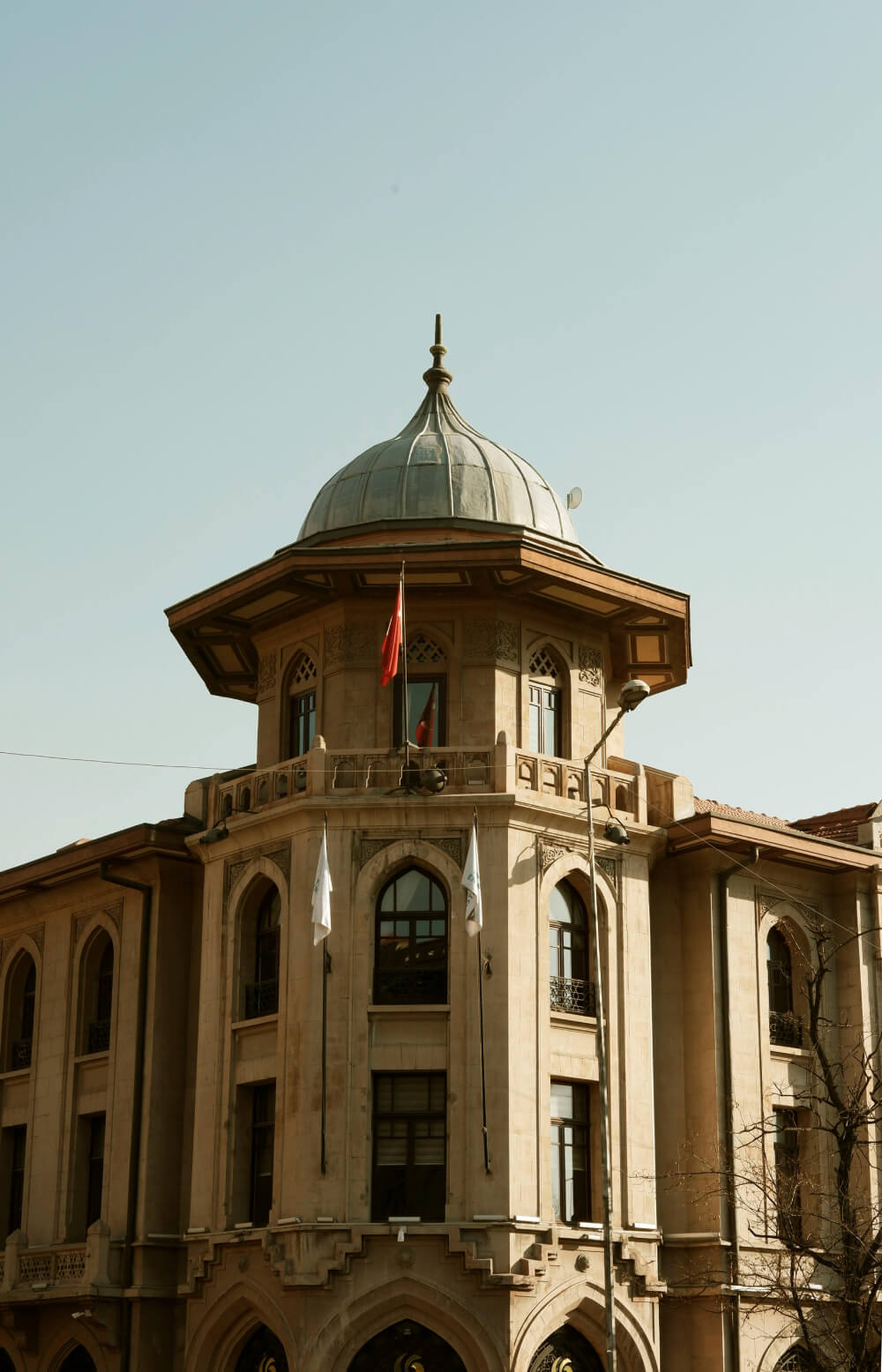 Historic beige stone building with arched windows and a domed roof under a clear sky.