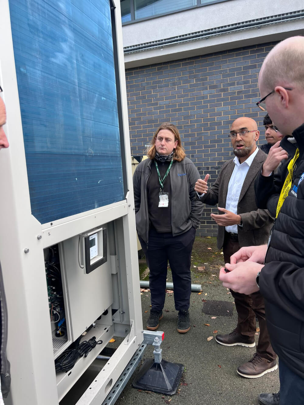ICG engineers examining and discussing a large industrial machine with exposed components.