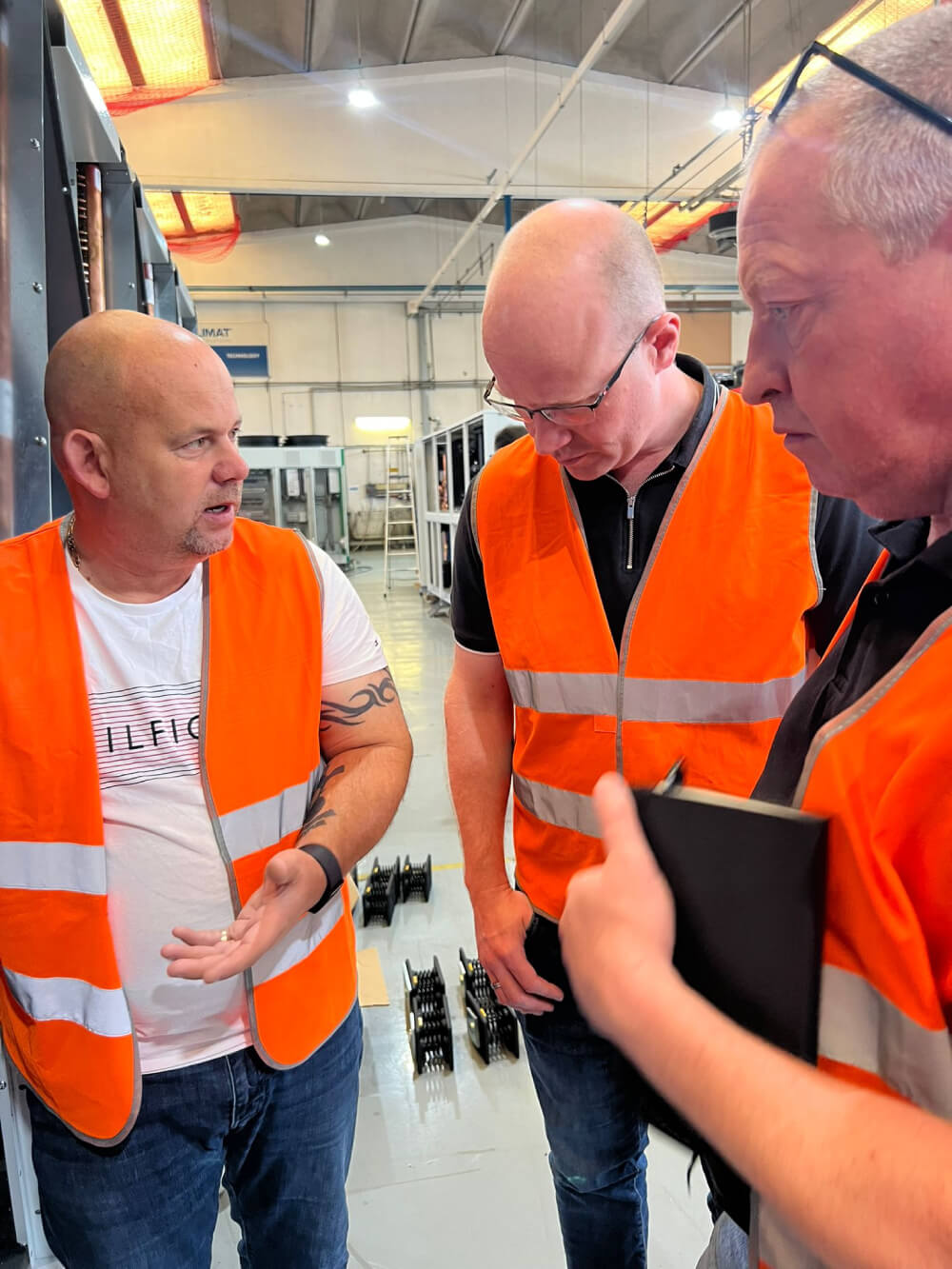 Three ICG engineers having a discussion inside a factory or warehouse.