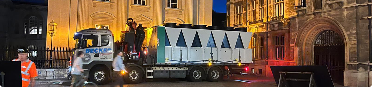 Hands wearing gloves adjusting a component on a commercial boiler control panel with digital temperature display.