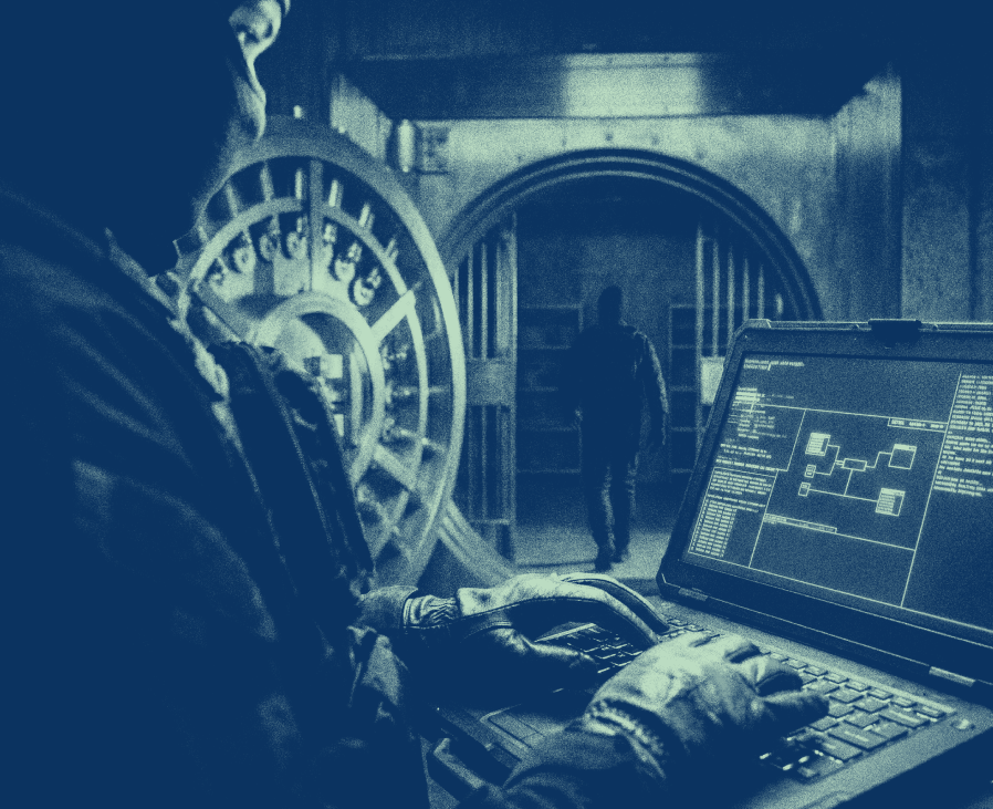 Gloved hands typing on a laptop showing a schematic, in front of an open bank vault with a shadowy figure inside.