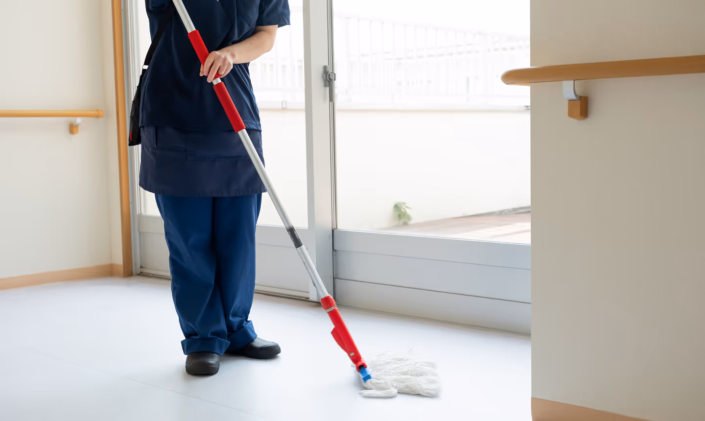 モップで床清掃を行う清掃スタッフ