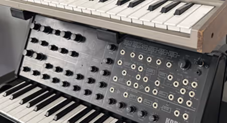 Synthétiseurs analogiques empilés avec claviers et panneaux de contrôle aux multiples boutons et prises.