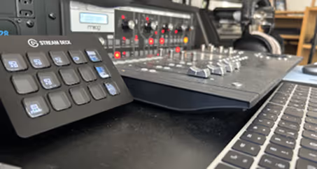 Plan de travail avec console de mixage audio, clavier d'ordinateur et clavier Stream Deck.