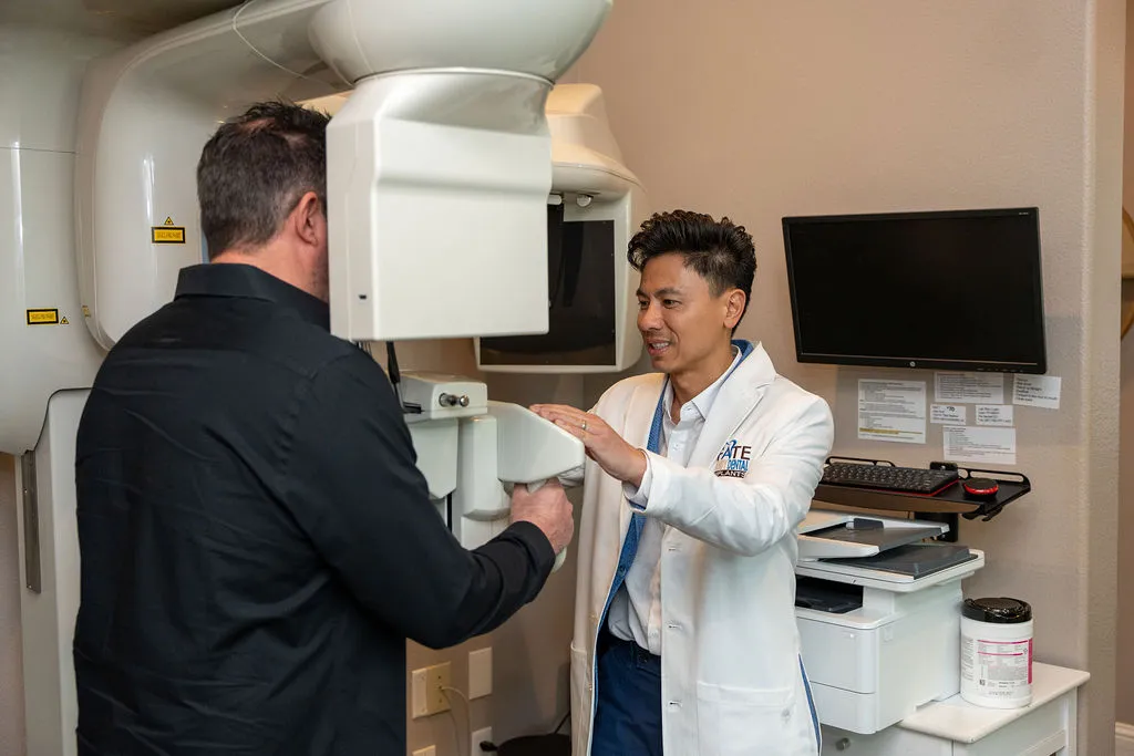 Dentist in a white coat assisting a man during a dental X-ray procedure.