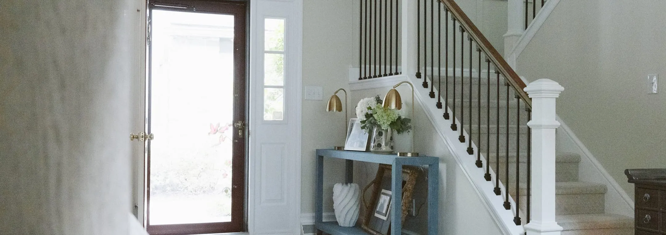 A hallway with a blue shelf and a white staircase.