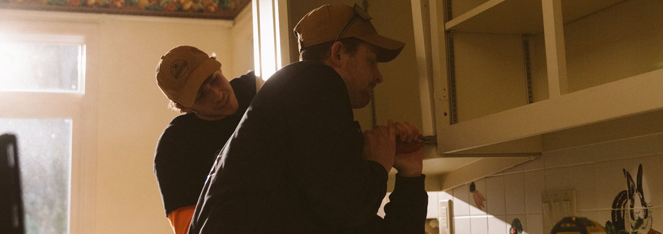 A couple of men standing next to each other in a kitchen.