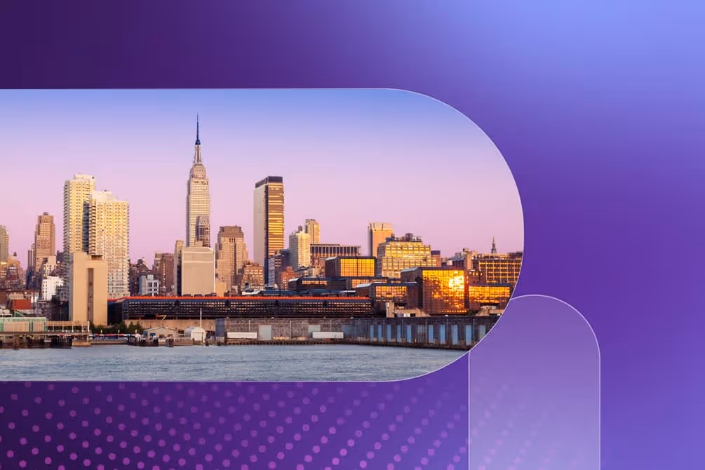 New York City skyline at sunset with buildings reflecting golden light over the water.