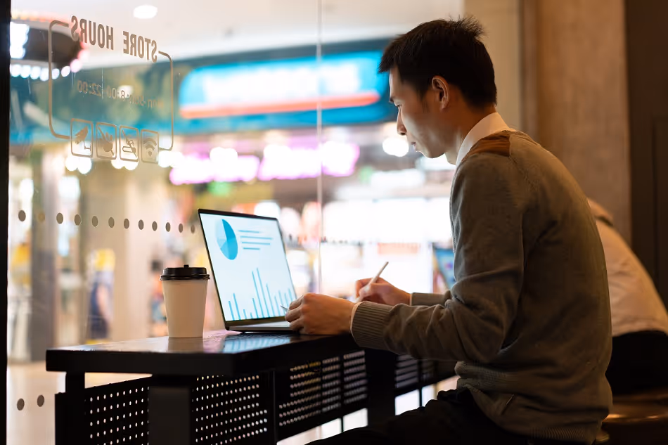 Asian man using laptop in shop