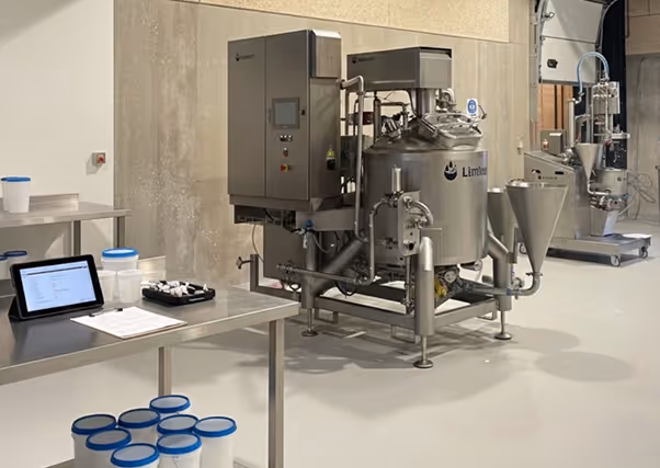 Industrial stainless steel mixing machine labeled 'Limtec' in a clean production room.
