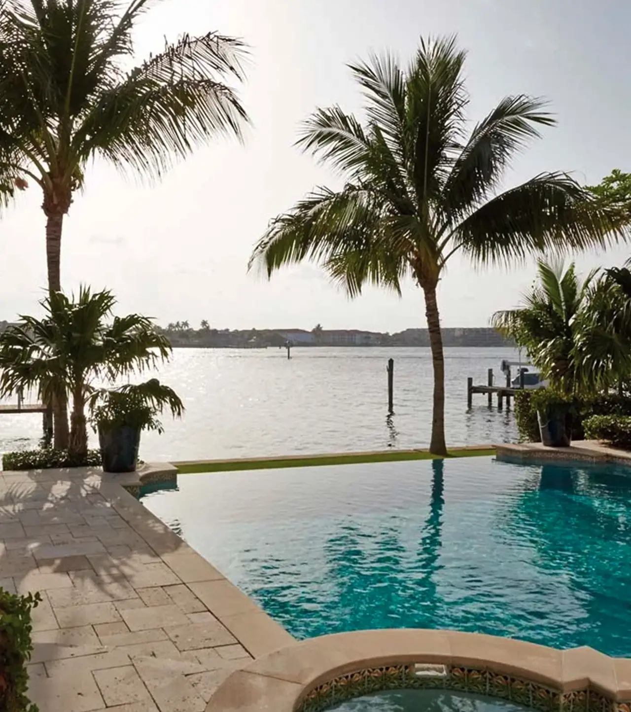 Waterfront pool and terrace framed by palm trees at a private residence