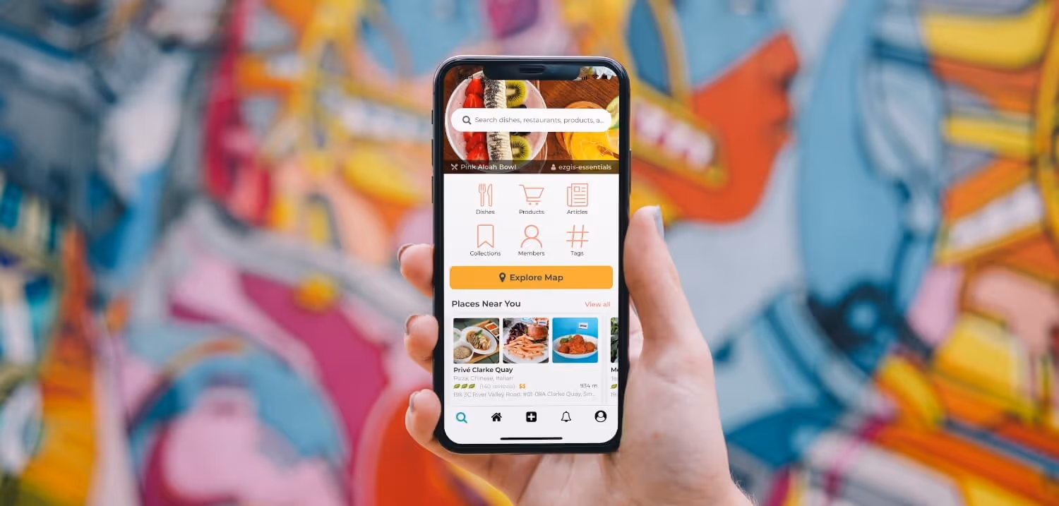 Hand holding smartphone displaying a restaurant app with search bar, category icons, explore map button, and nearby places list.